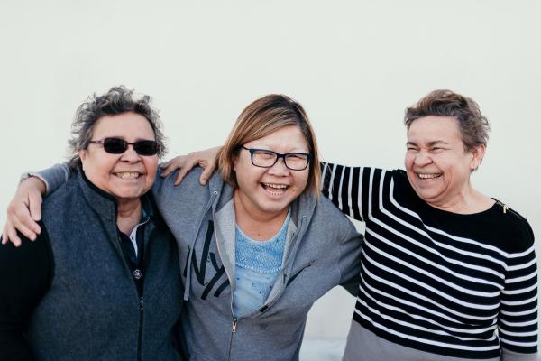 Three older women laughing with arms around each other